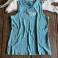 Blue tank top with a logo on a wooden surface next to a cowhide rug