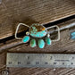 Turquoise and silver twilly slide on a wooden surface with a ruler for scale.