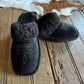 Black slippers with fuzzy texture on a wooden floor
