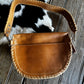 Brown leather handbag on a wooden surface with cowhide rug