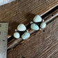 Jewelry with white stones on a wooden surface next to a ruler for scale.