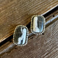 Pair of earrings with stone and gold accents on a wooden surface