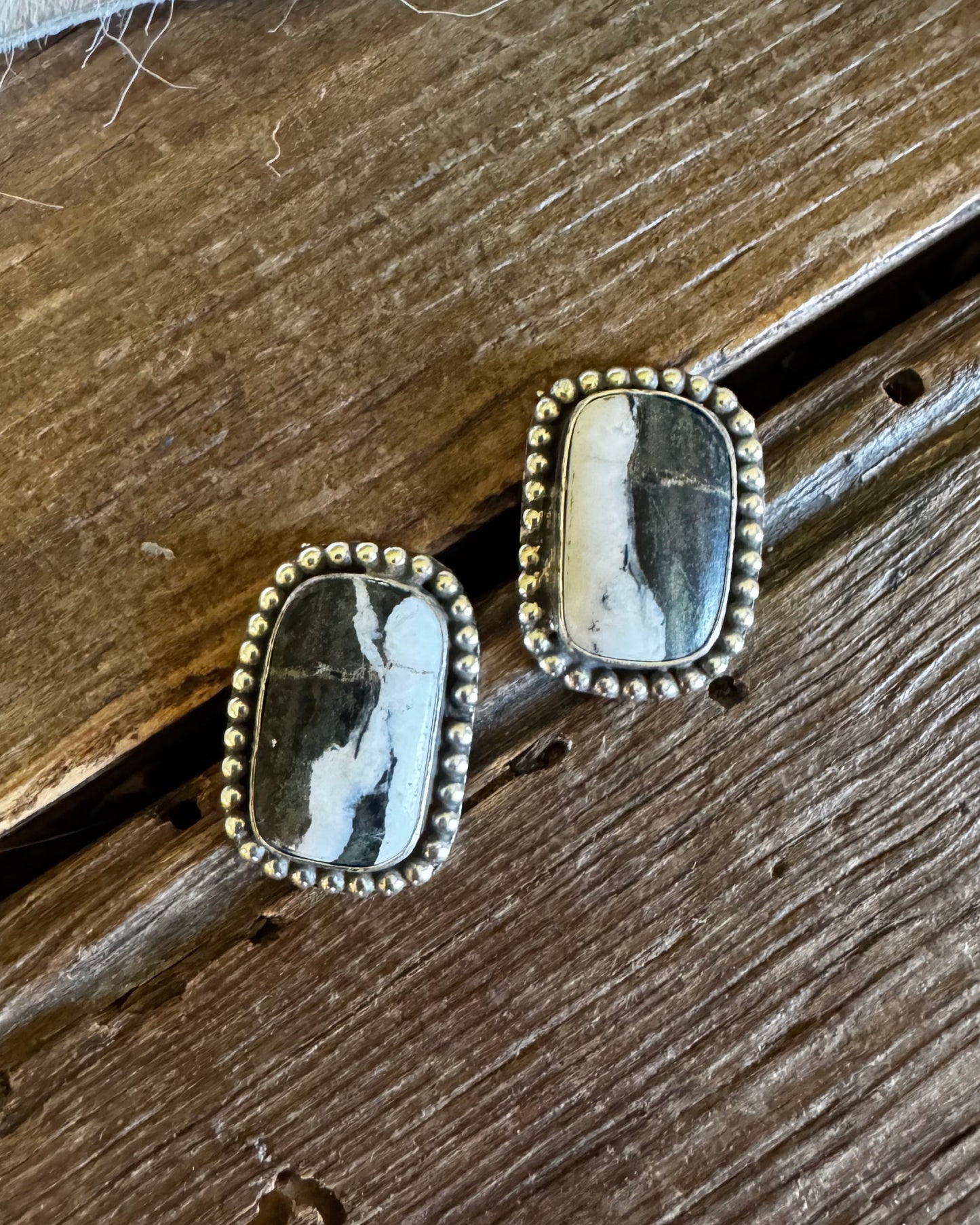 Pair of earrings with stone and gold accents on a wooden surface