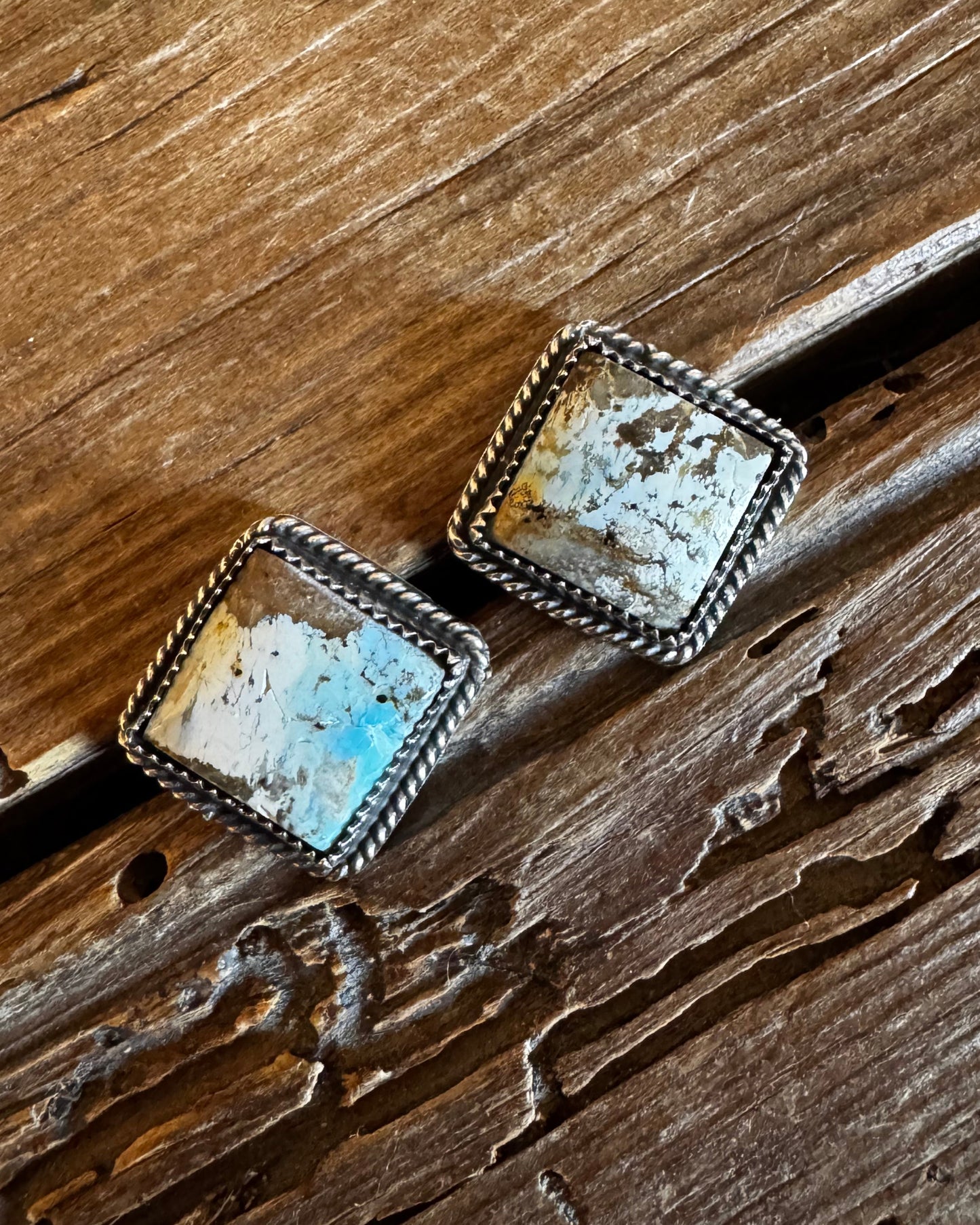 Square stone earrings on a wooden surface