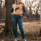 Model standing in trees, dressed in a stylish modern western outfit.