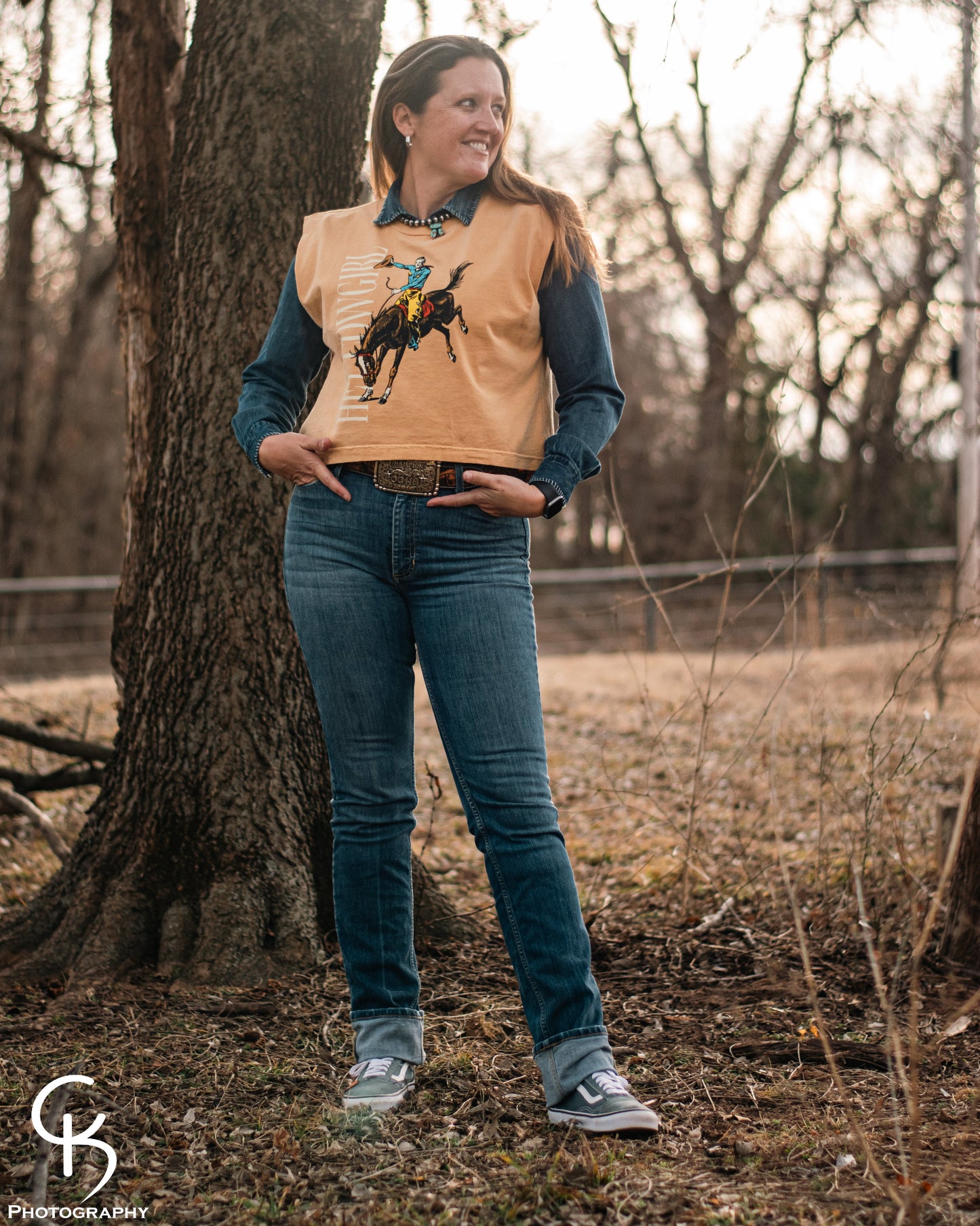 Model standing in trees, dressed in a stylish modern western outfit.