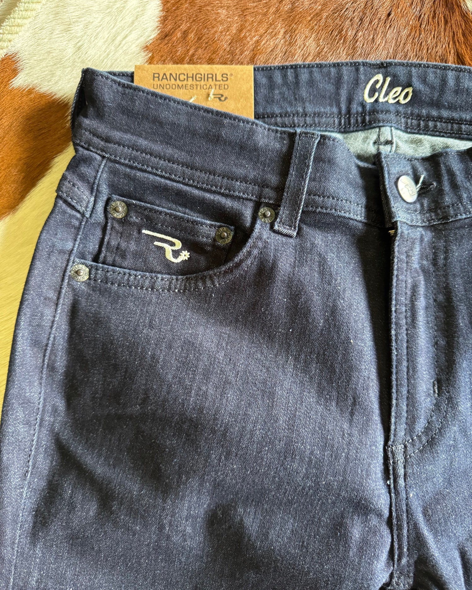 Close-up of a blue denim jacket with brand labels on a textured surface