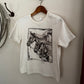 White t-shirt with horse graphic on a hanger against a white wall.