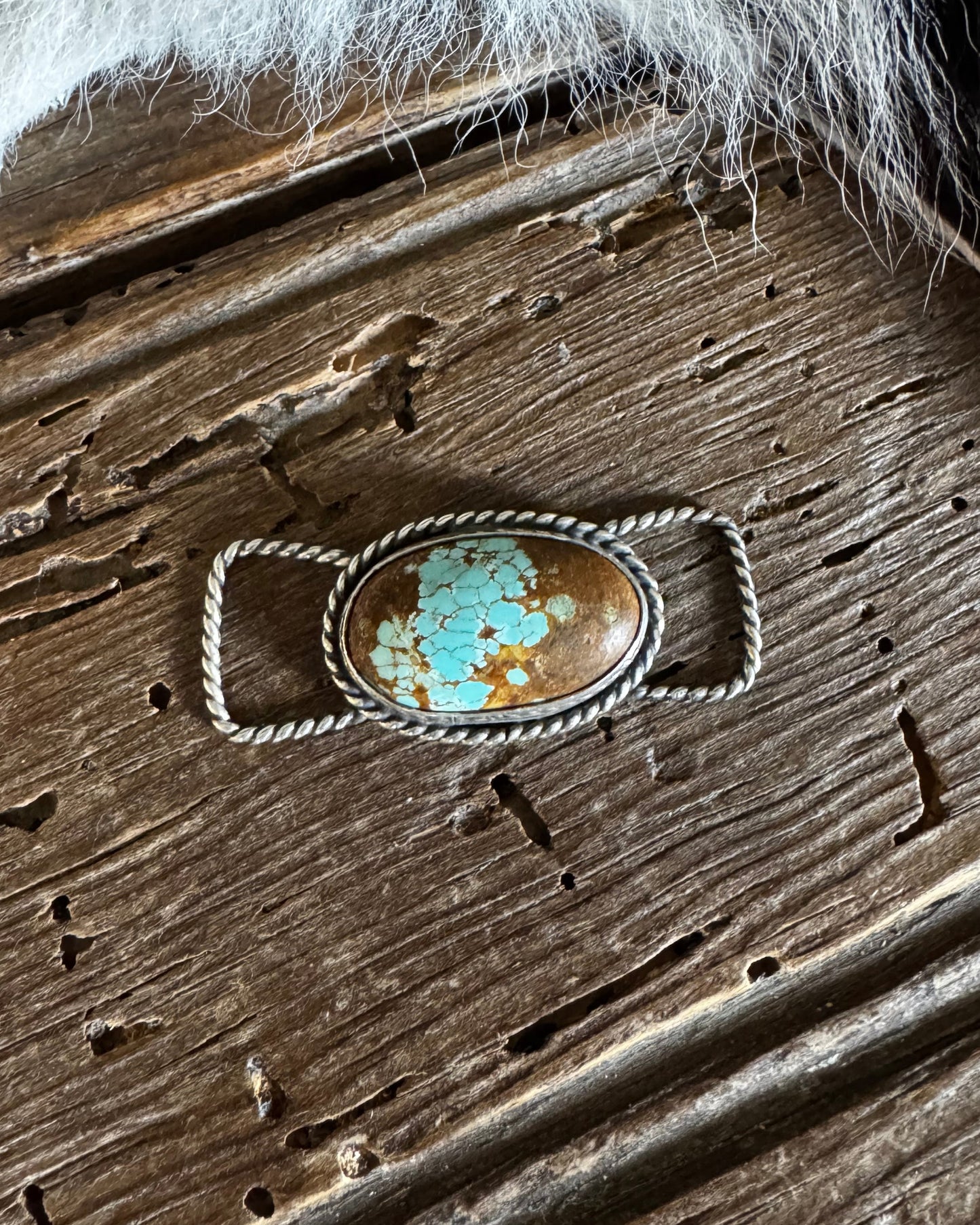 Turquoise stone ring on a wooden surface with fur on the side