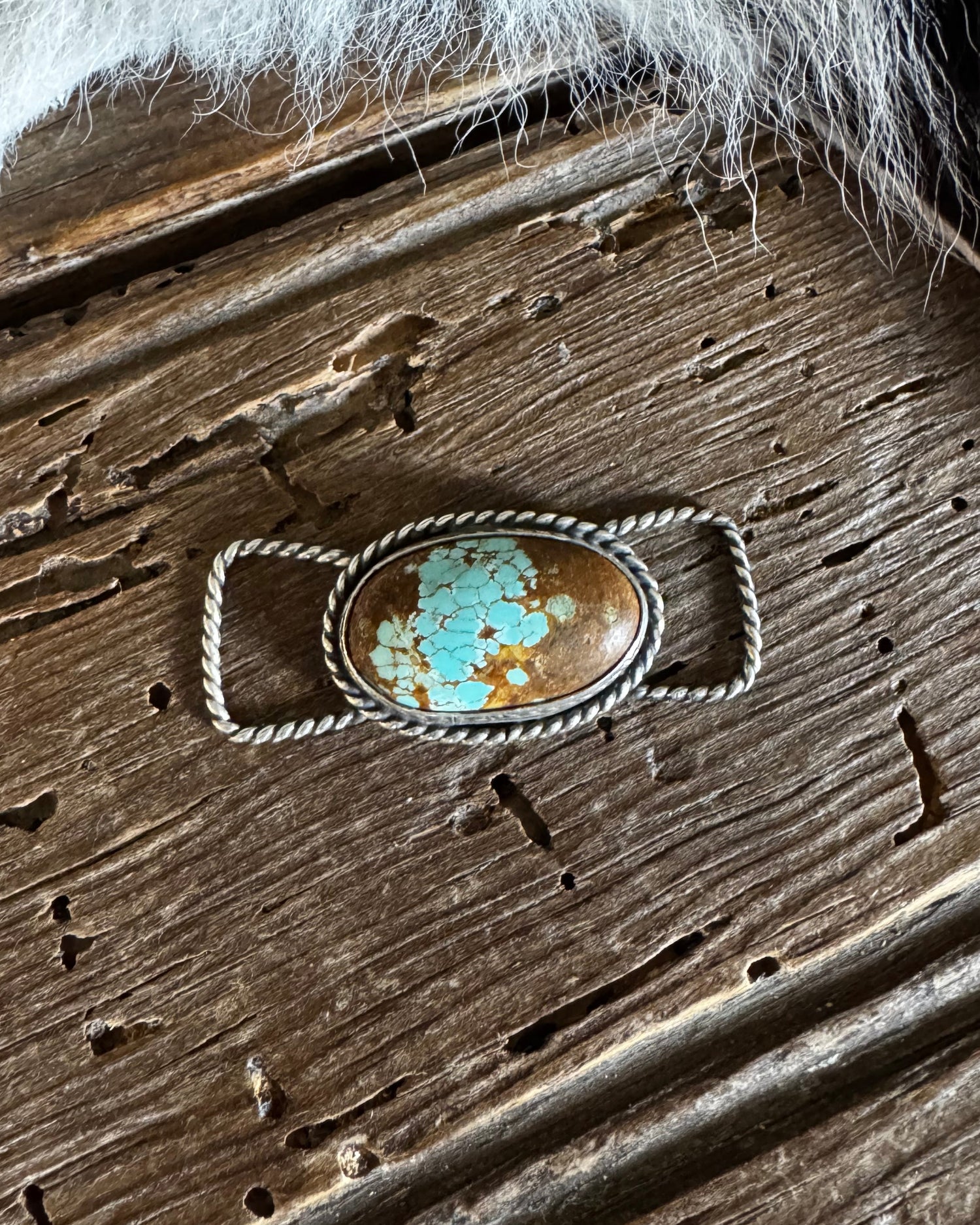 Turquoise stone ring on a wooden surface with fur on the side