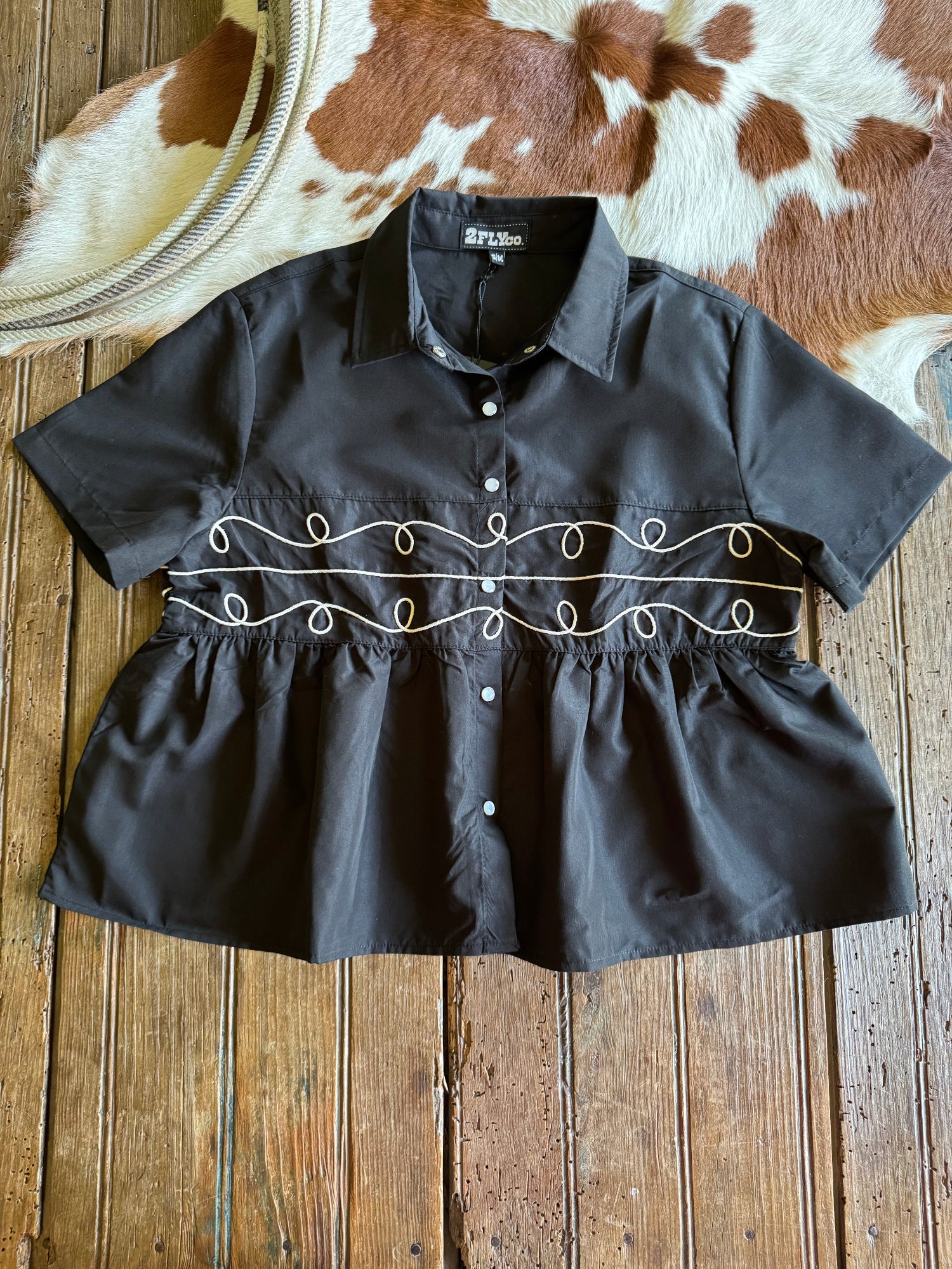 Black blouse with decorative embroidery on a wooden surface