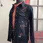 Black denim shirt with embroidered designs on a mannequin against a neutral background.
