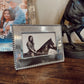 Decorative photo frame with a picture of a person on a horse inside, placed on a wooden surface.