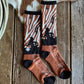 Pair of patterned socks on a wooden surface with a cowhide rug and rope.