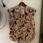 Sleeveless blouse with western print hanging on a white wall