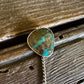 Turquoise stone brooch on a wooden surface