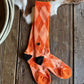 Orange socks on a wooden surface with a cow's hide in the corner