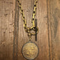 Gold chain with a medallion on a wooden surface