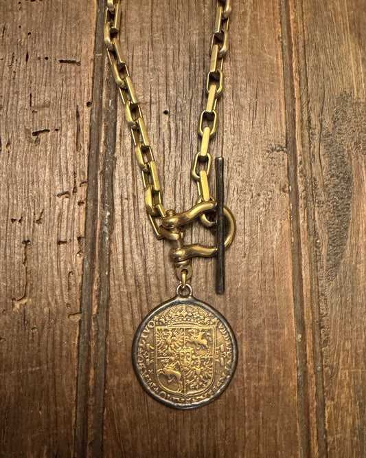 Gold chain with a medallion on a wooden surface