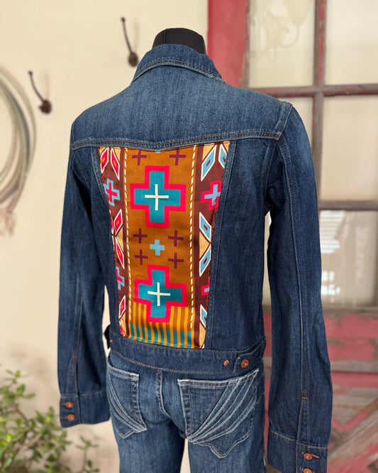 Denim jacket with a colorful pattern on the back, displayed on a mannequin.