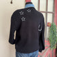 Mannequin wearing a black sweater with star patterns in front of a red door.