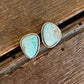 Turquoise stone earrings on a wooden surface