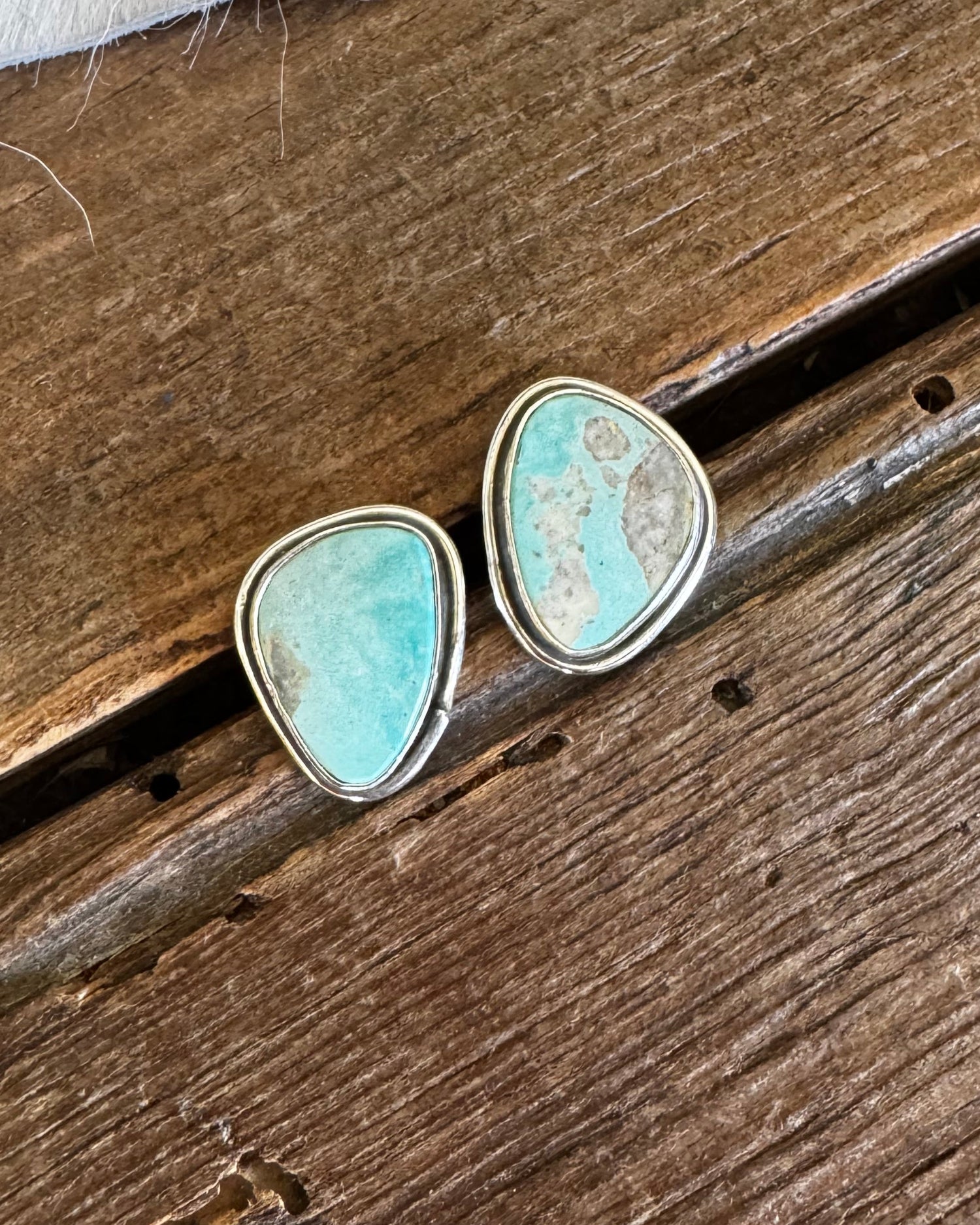 Turquoise stone earrings on a wooden surface