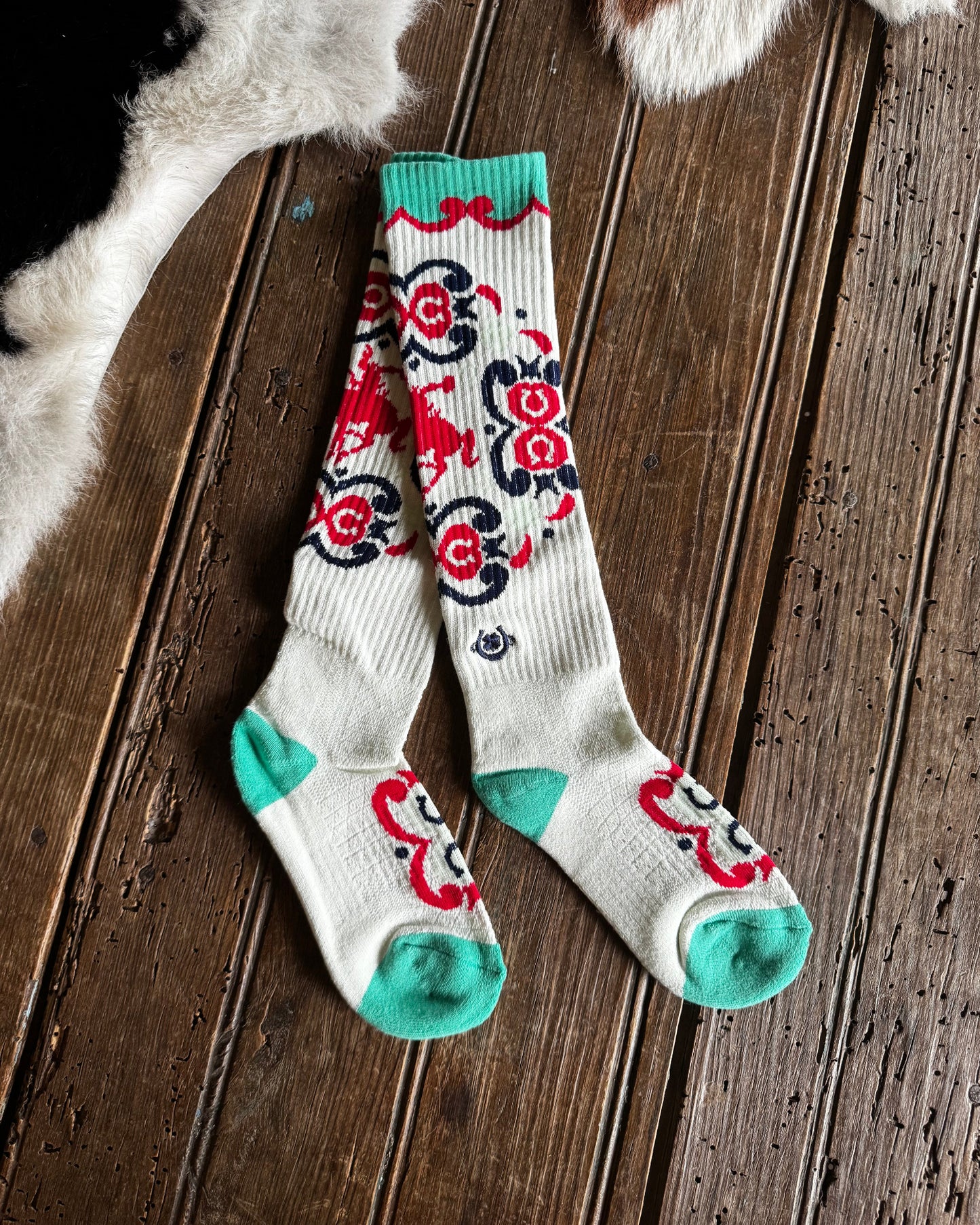 Pair of patterned socks on a wooden floor with cowhide rug