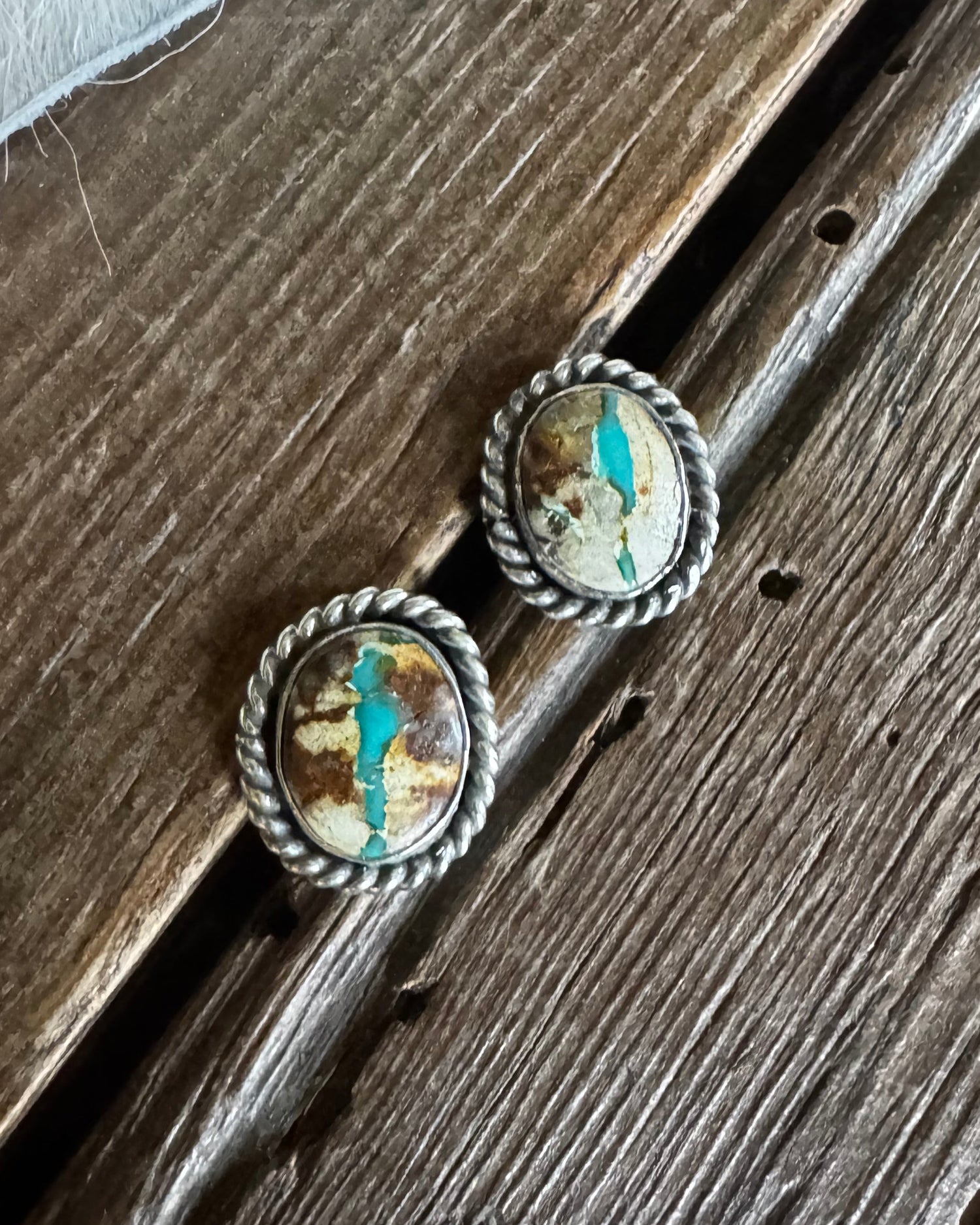 Pair of silver earrings with turquoise stones on a wooden surface
