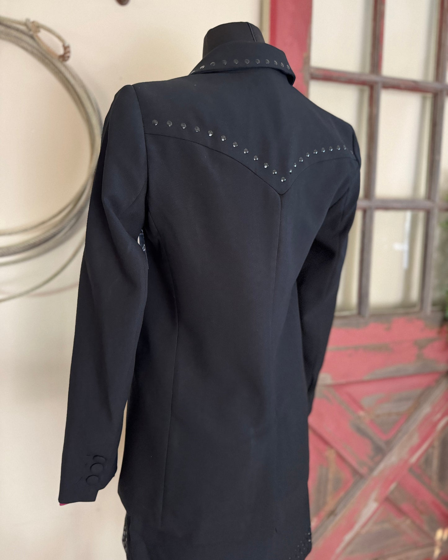 Black jacket with studded details on a mannequin against a neutral background