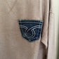 Close-up of a beige corduroy shirt with a brand logo on the pocket.