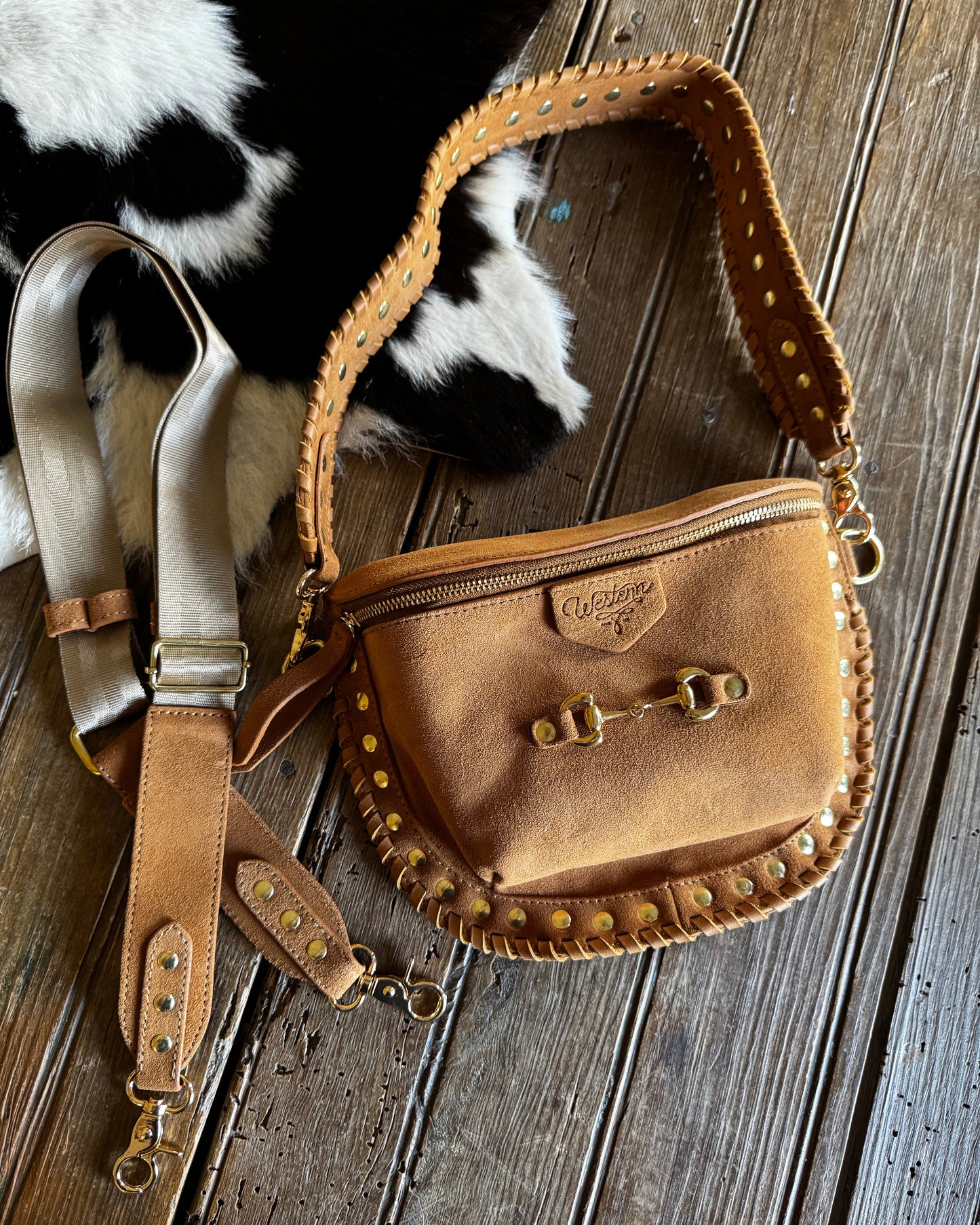Brown leather bag with gold studs on a wooden surface