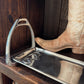 Metal stirrup on a wooden surface with a cowboy boot partially inside it