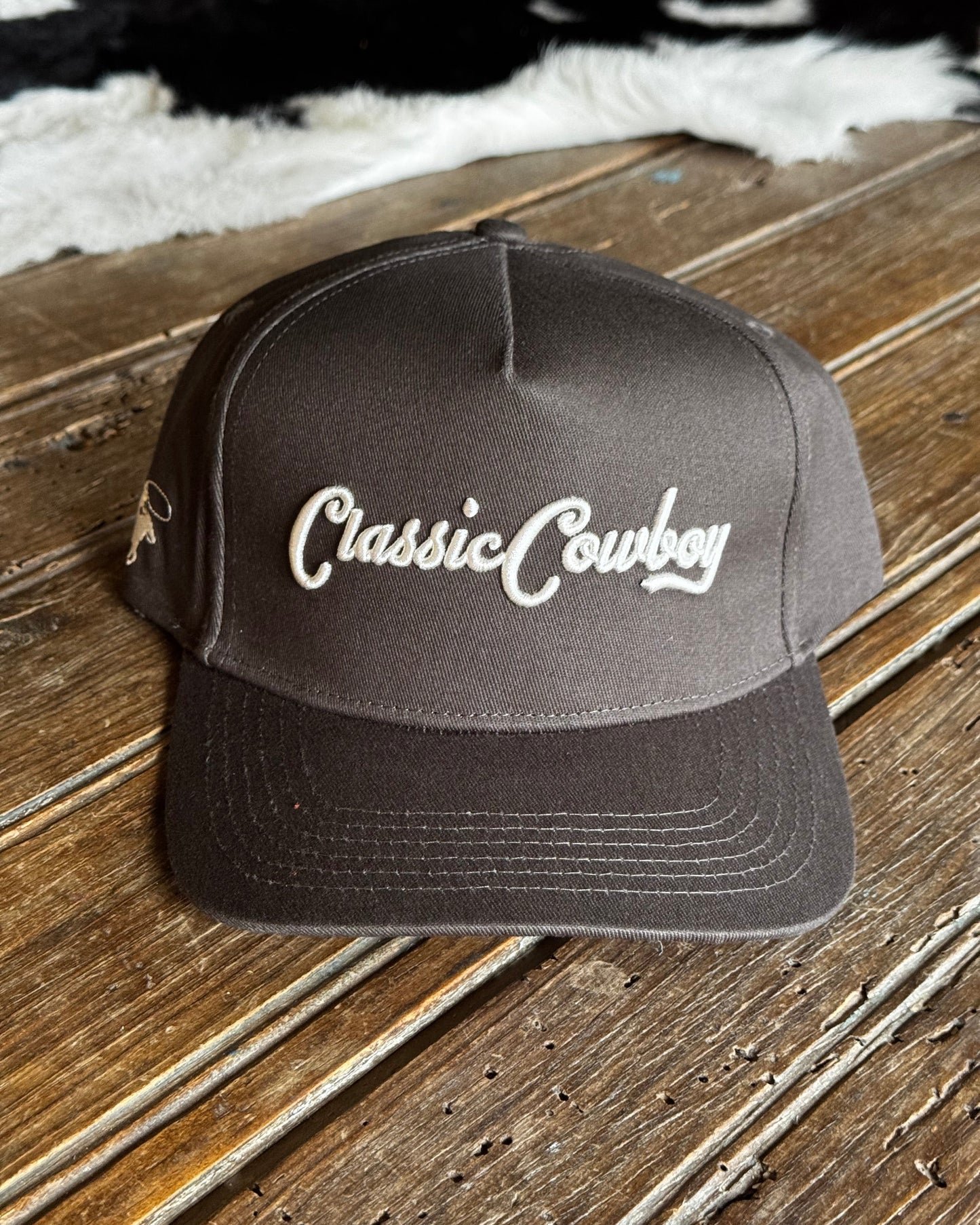 Dark gray cap with 'Classic Cowboy' logo on a wooden surface