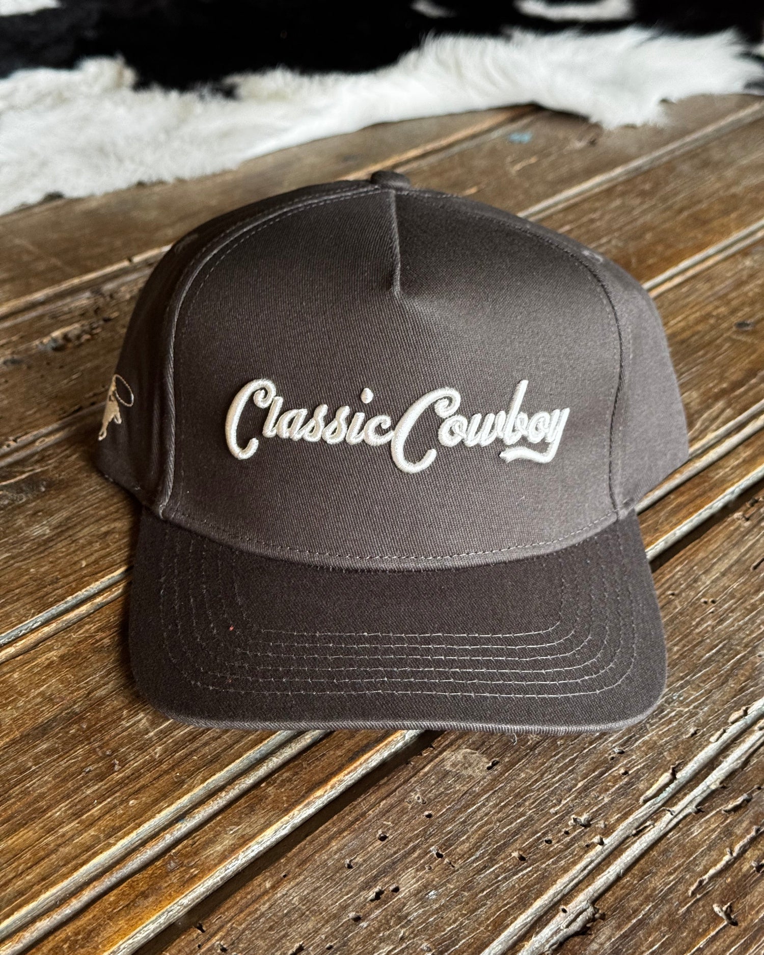 Dark gray cap with 'Classic Cowboy' logo on a wooden surface