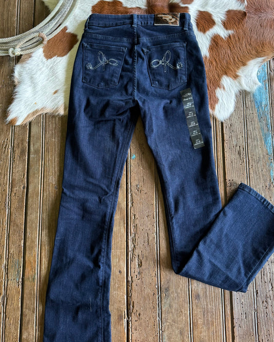 Blue jeans with floral embroidery on a wooden surface with cowhide rug