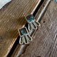 Silver earrings with green gemstones on a wooden surface