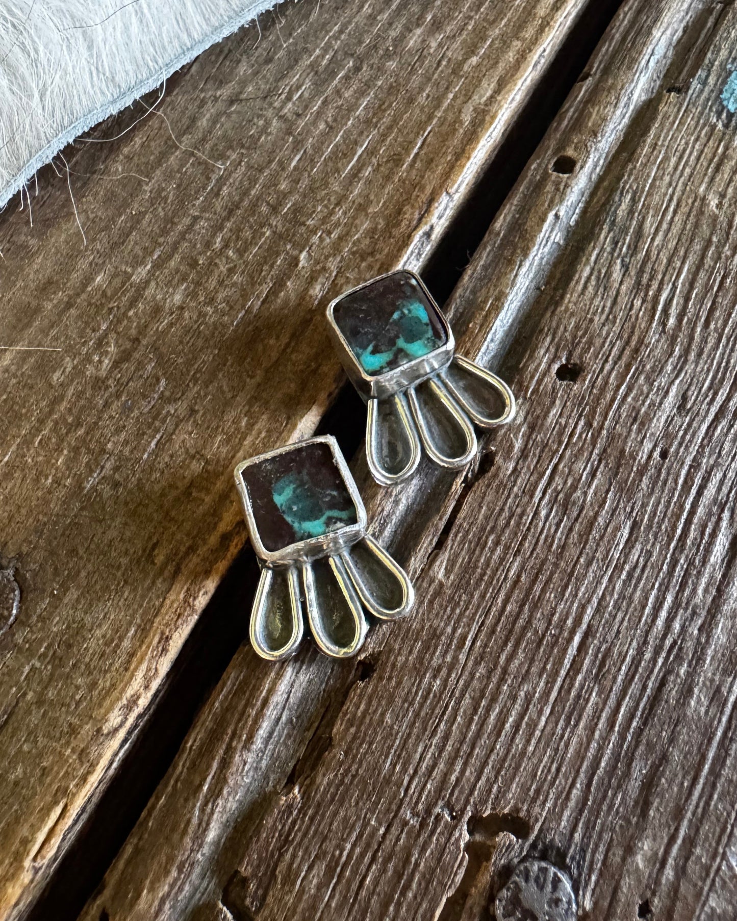 Silver earrings with green gemstones on a wooden surface
