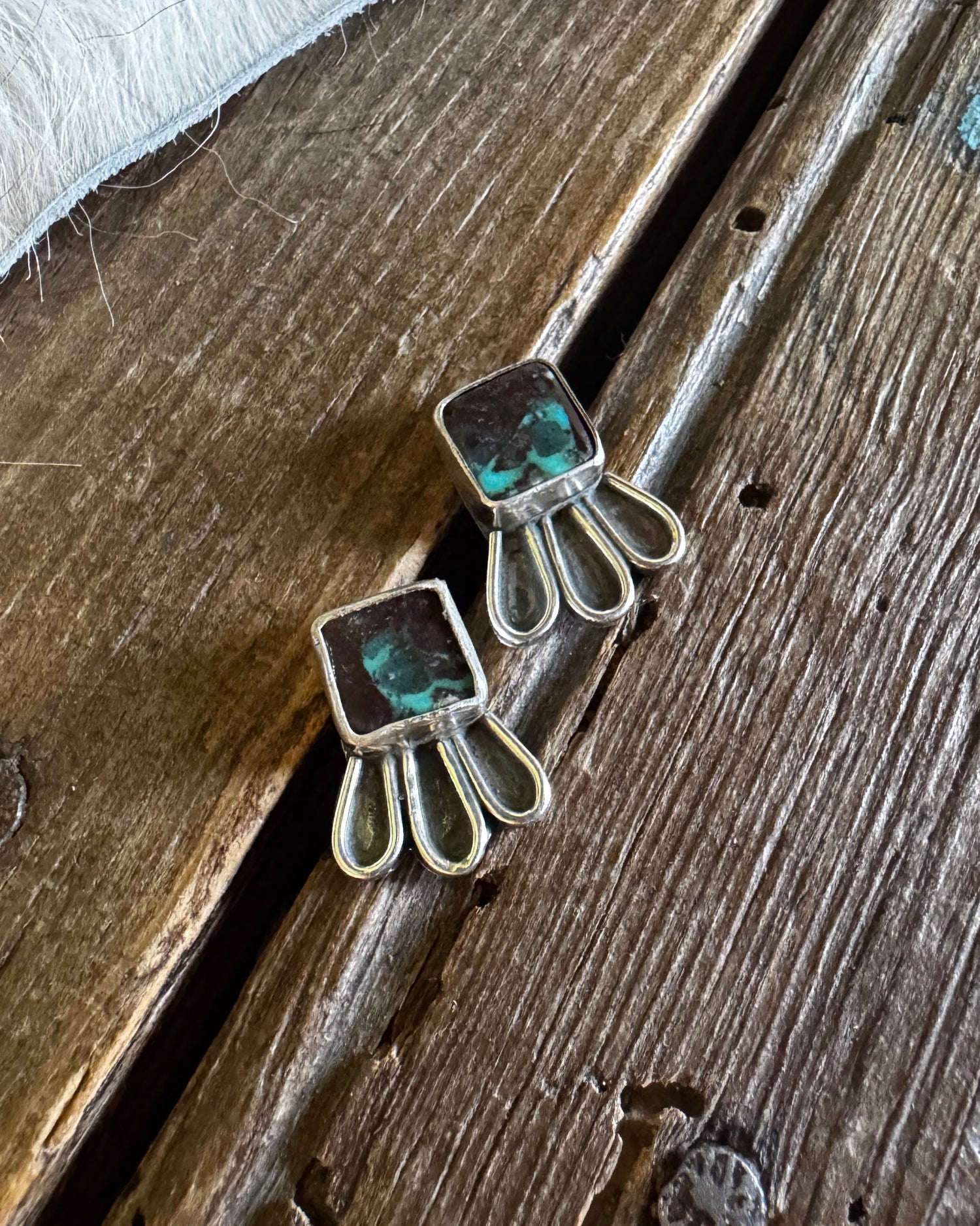 Silver earrings with green gemstones on a wooden surface