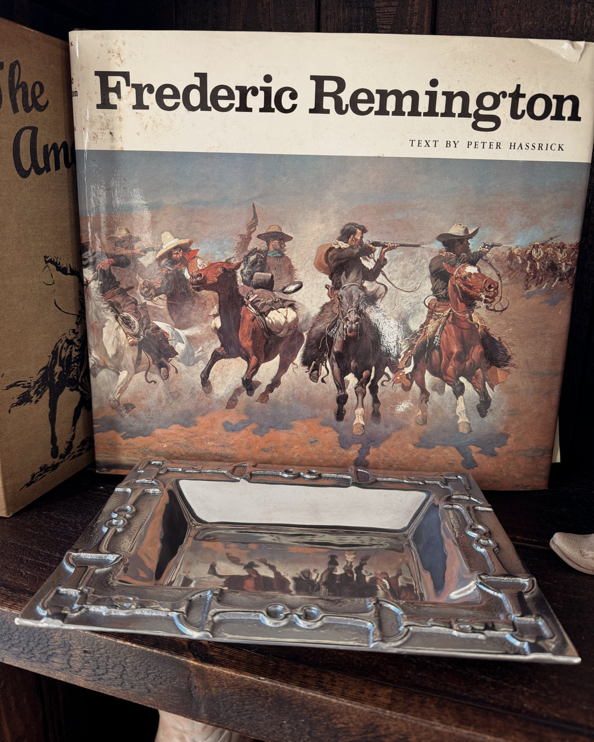 Book titled 'Frederic Remington' with a silver tray in front on a wooden surface
