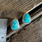 Turquoise stud earrings on a wooden surface with a ruler for scale.
