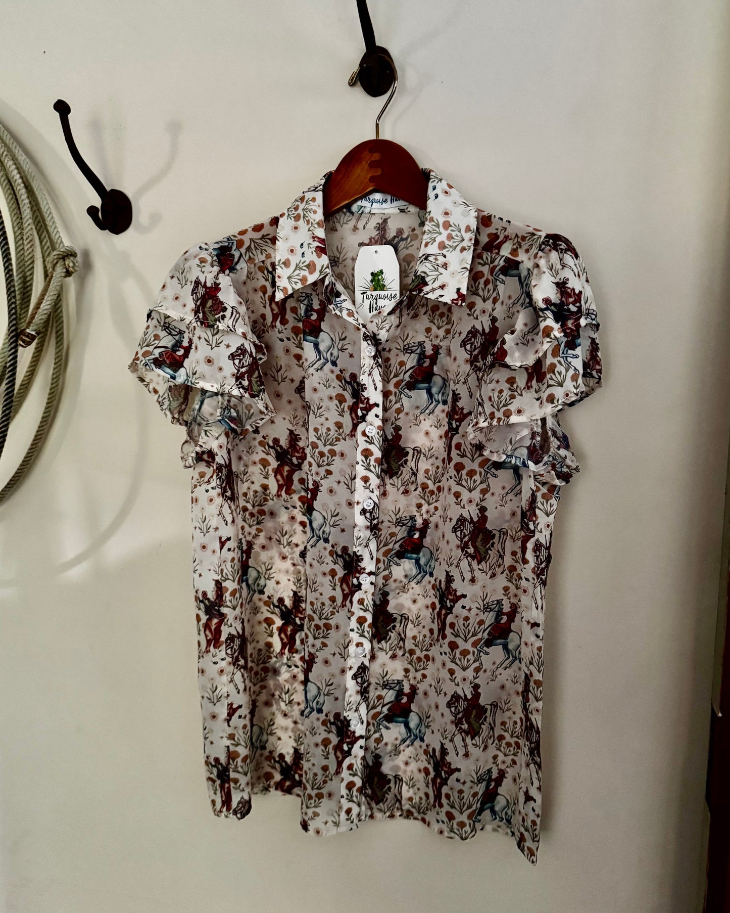 Floral patterned shirt hanging on a hook against a white wall.
