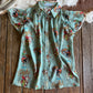 Turquoise blouse with cowboy pattern on a wooden surface