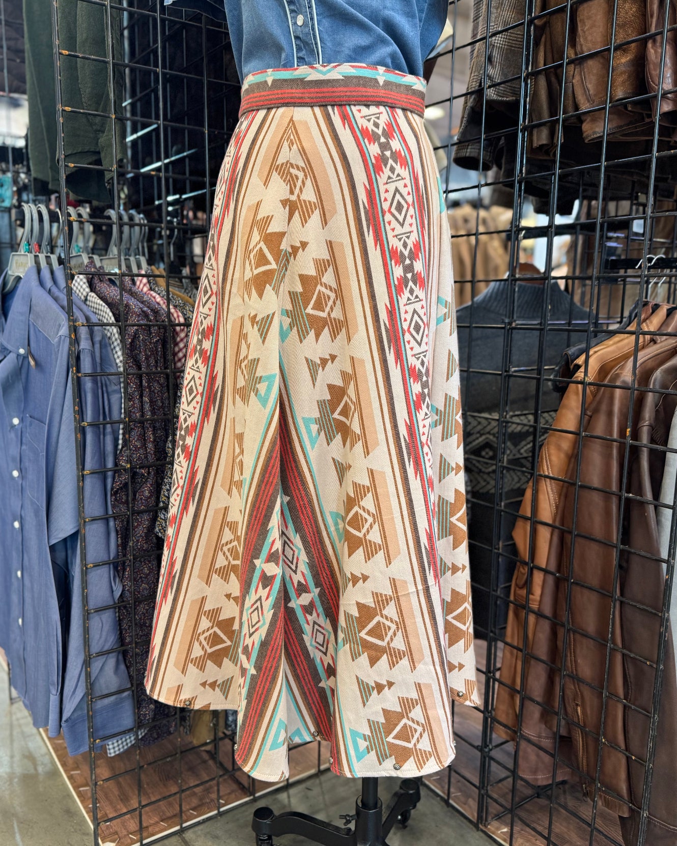 Patterned skirt on a mannequin in a store setting with clothing racks.