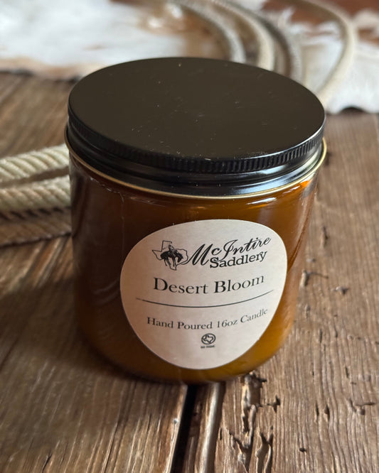 Jar of desert bloom candle with a label on a wooden surface