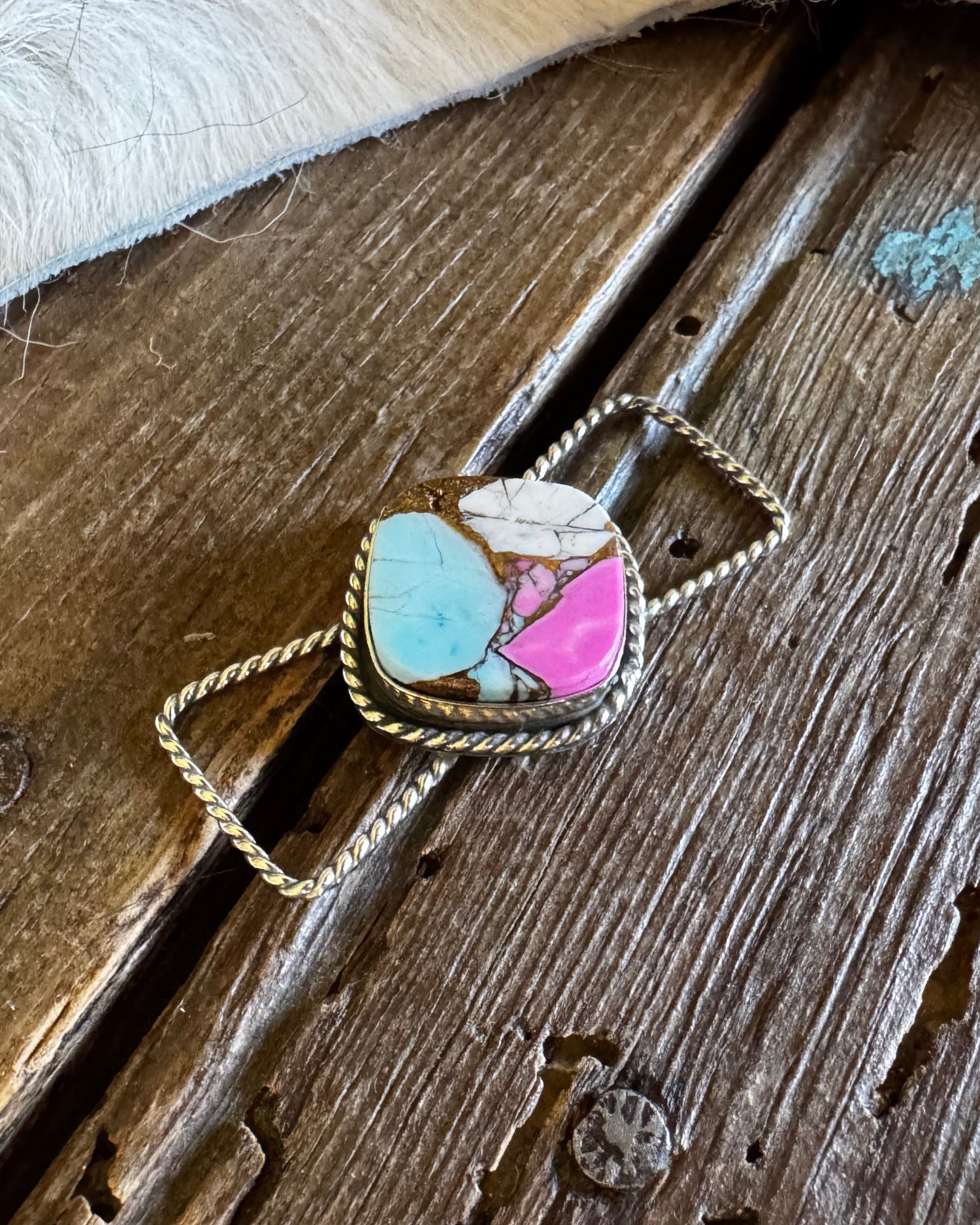 Twilly slide with a multicolored stone pendant on a wooden surface