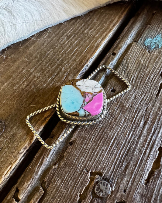 Twilly slide with a multicolored stone pendant on a wooden surface