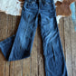 Blue jeans on a wooden surface with a cowhide rug in the background