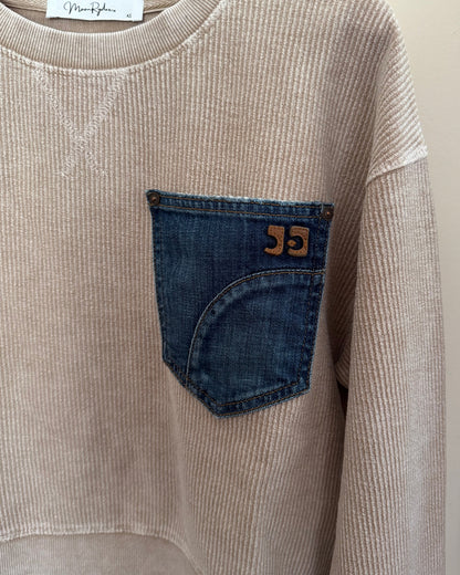 Beige corduroy shirt with a blue pocket and brand label on a light background