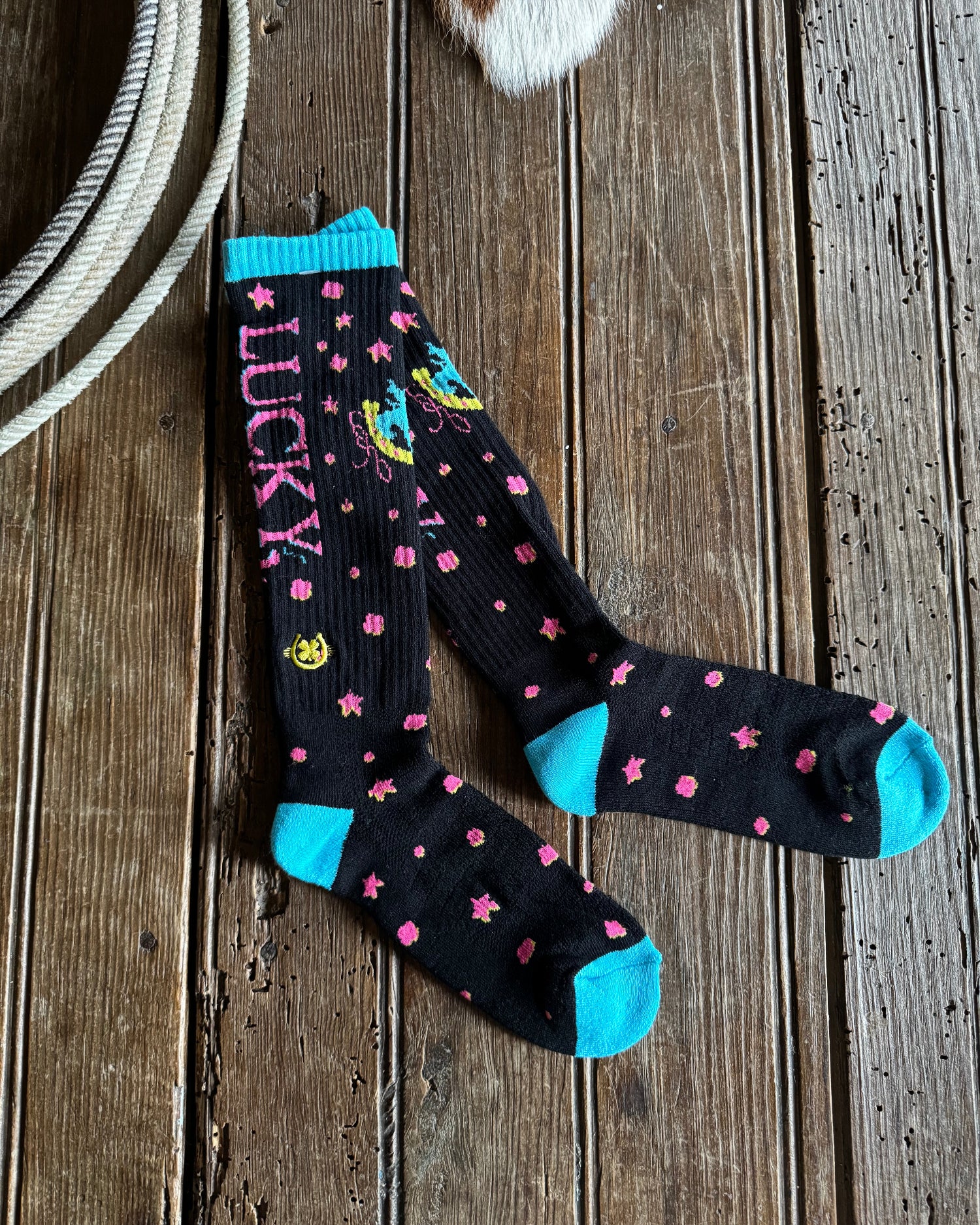 Black socks with pink stars and blue accents on a wooden surface